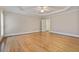 Bright bedroom featuring hardwood floors, tray ceiling, and a ceiling fan along with windows with shuttered blinds at 3105 Birchton St, Johns Creek, GA 30022