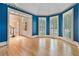 Bright living room featuring hardwood floors, blue accent wall, large windows with shutters, and an arched doorway at 3105 Birchton St, Johns Creek, GA 30022