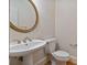 Powder room featuring pedestal sink, brass fixtures, and a round mirror at 3105 Birchton St, Johns Creek, GA 30022