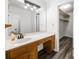 Bathroom vanity featuring wooden cabinets, sink, and a mirror with ample lighting, plus a view of the walk-in closet at 3400 Bonds Lake Nw Rd, Conyers, GA 30012