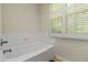 A tiled bathtub with tile surround and window with wood shutters at 2400 Cumberland Se Pkwy # 803, Atlanta, GA 30339