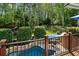 Beautiful backyard with a pool, hot tub, stone walls, manicured bushes, and a view of the surrounding greenery at 3115 Corsair Curv, Cumming, GA 30040