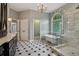 Bright bathroom with a free standing tub, walk-in shower, arched window, and black and white floors at 3115 Corsair Curv, Cumming, GA 30040