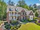 Elegant two-story brick home featuring a lush front yard, manicured landscaping, and a welcoming entrance at 3115 Corsair Curv, Cumming, GA 30040