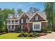 Charming two-story brick home with a lush front yard, manicured landscaping, and a welcoming front porch at 3115 Corsair Curv, Cumming, GA 30040