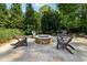 Stone patio with a charming stone fire pit and seating surrounded by lush greenery and mature trees at 3115 Corsair Curv, Cumming, GA 30040