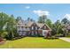 Beautiful brick home with dormer windows and second story porch, surrounded by lush greenery and landscaping at 3115 Corsair Curv, Cumming, GA 30040