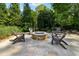 Inviting backyard patio with stone fire pit and comfortable seating surrounded by mature landscaping at 3115 Corsair Curv, Cumming, GA 30040