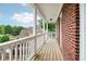 Inviting covered porch with wooden floors, white railing, and red brick exterior walls at 3115 Corsair Curv, Cumming, GA 30040