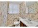 Cozy half-bathroom featuring floral wallpaper, a white sink, and a toilet, creating a charming space at 5618 Fern Creek Sw Dr, Lilburn, GA 30047