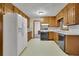 Functional kitchen with wood cabinets, white appliances, and adjoining dining area with view to other rooms at 5618 Fern Creek Sw Dr, Lilburn, GA 30047
