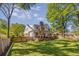Beautiful backyard view of home with mature trees, lush green grass, a wooden fence, and outdoor seating at 1256 Spring Valley Ne Ln, Atlanta, GA 30306