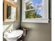 Half bathroom with a window, pedestal sink, framed mirror, and olive green walls at 1256 Spring Valley Ne Ln, Atlanta, GA 30306