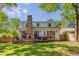 Back exterior of home with large brick chimney, French doors to patio, and well-maintained lawn at 1256 Spring Valley Ne Ln, Atlanta, GA 30306