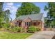 Charming brick home featuring a well-manicured lawn, mature trees, and welcoming front porch at 1256 Spring Valley Ne Ln, Atlanta, GA 30306