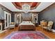 Luxurious main bedroom features a tray ceiling, four-poster bed, chandelier, and a seating area at 2120 Blackheath Trce, Alpharetta, GA 30005