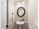 Elegant powder room featuring a pedestal sink, decorative mirror, and stylish lighting at 720 Lakeglen Dr, Suwanee, GA 30024