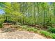 Tranquil backyard with stone patio surrounded by lush greenery and mature trees at 8215 Majors Mill Dr, Cumming, GA 30041