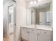 Bright bathroom with large mirror, white vanity with storage, and doorway view of another vanity at 8215 Majors Mill Dr, Cumming, GA 30041