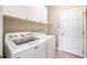 Bright laundry room with white cabinets, modern machines, and doorway to outside at 8215 Majors Mill Dr, Cumming, GA 30041