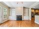Bright living room with hardwood floors, built-in bookshelves, fireplace, and double ovens adjacent to the kitchen at 8215 Majors Mill Dr, Cumming, GA 30041