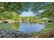 Scenic pond view lined with mature trees and lush landscaping at 400 Mirramont Ln, Woodstock, GA 30189