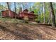 Spacious back porch and deck of a log home in a wooded backyard provides ample room for outdoor seating at 6515 Namon Wallace Dr, Cumming, GA 30028