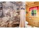Cozy bathroom with a stone-look shower, wooden walls, and natural light from the window at 6515 Namon Wallace Dr, Cumming, GA 30028