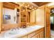 Bathroom featuring double sinks, bright lighting, and wooden cabinets with a decorative mirror at 6515 Namon Wallace Dr, Cumming, GA 30028