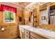 Well-lit bathroom with double sinks, wooden cabinetry, and a window with a scenic outdoor view at 6515 Namon Wallace Dr, Cumming, GA 30028