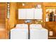 Efficient laundry room with front-load machines, storage cabinets, and rustic wooden walls at 6515 Namon Wallace Dr, Cumming, GA 30028