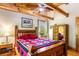 Cozy main bedroom featuring a bed frame with exposed beams and a colorful quilt at 6515 Namon Wallace Dr, Cumming, GA 30028