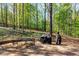 Stone patio with outdoor seating and BBQ grill backs to a wooded landscape, perfect for entertaining at 6515 Namon Wallace Dr, Cumming, GA 30028