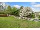 Green lawn with a white wooden fence and blooming dogwood tree adding charm to the property at 3920 Maybreeze Rd, Marietta, GA 30066