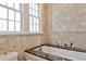 Bright bathroom featuring a soaking tub with marble surround, double hung windows and tile detailing at 272 Rumson Ne Rd, Atlanta, GA 30305