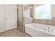 Modern bathroom features a soaking tub, a glass-enclosed shower and light tile floors at 802 Milo Bay St, Loganville, GA 30052