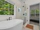 Bright bathroom showcasing tub, glass enclosed shower, and wooded view at 5071 Woodmont Dr, Villa Rica, GA 30180