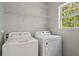 Well-lit laundry room featuring washer, dryer, wire shelving, and a window for natural light at 5071 Woodmont Dr, Villa Rica, GA 30180
