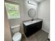 A well-lit bathroom featuring a window and a dark vanity with granite countertop at 1341 E Atlanta E Rd, Stockbridge, GA 30281