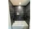 A view of a bathtub with black tiled walls and a shower head at 1341 E Atlanta E Rd, Stockbridge, GA 30281
