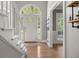 Bright entryway with hardwood floors, white staircase, and arched transom window over the front door at 7389 Tidewater Trce, Stone Mountain, GA 30087