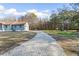 Long gravel driveway leading to a charming home with a spacious front yard and mature trees at 900 Stone Lea Trce, Oxford, GA 30054