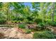 Lush backyard features a stone-lined koi pond and brick paver path surrounded by gardens at 204 Overland Trl, Mcdonough, GA 30252