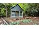 Quaint outbuilding with a covered porch, steps, and a picnic table, surrounded by greenery at 204 Overland Trl, Mcdonough, GA 30252