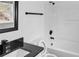 Modern bathroom features a tub with shower, black hardware, and a granite vanity top at 3094 Jonesboro St, Ellenwood, GA 30294