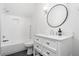 Bright bathroom featuring a tub and shower combination, all-white tile, and a round mirror at 216 Haralson Ne Ln, Atlanta, GA 30307