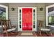 Inviting front porch with rocking chairs, a vibrant red door, and decorative lighting fixtures at 5876 Bridgemont Nw Pl, Acworth, GA 30101