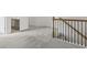 Upstairs hallway with neutral walls and gray carpet with wood and black iron railing and view of bathroom at 529 Lanier Way, Temple, GA 30179