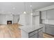 Open-concept kitchen with gray cabinets, hardwood floors, granite countertops, island, and fireplace at 529 Lanier Way, Temple, GA 30179