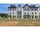 Modern townhomes with white brick, gray accents, dormer windows, and professionally landscaped front yards at 529 Rubato Knl, Mcdonough, GA 30253